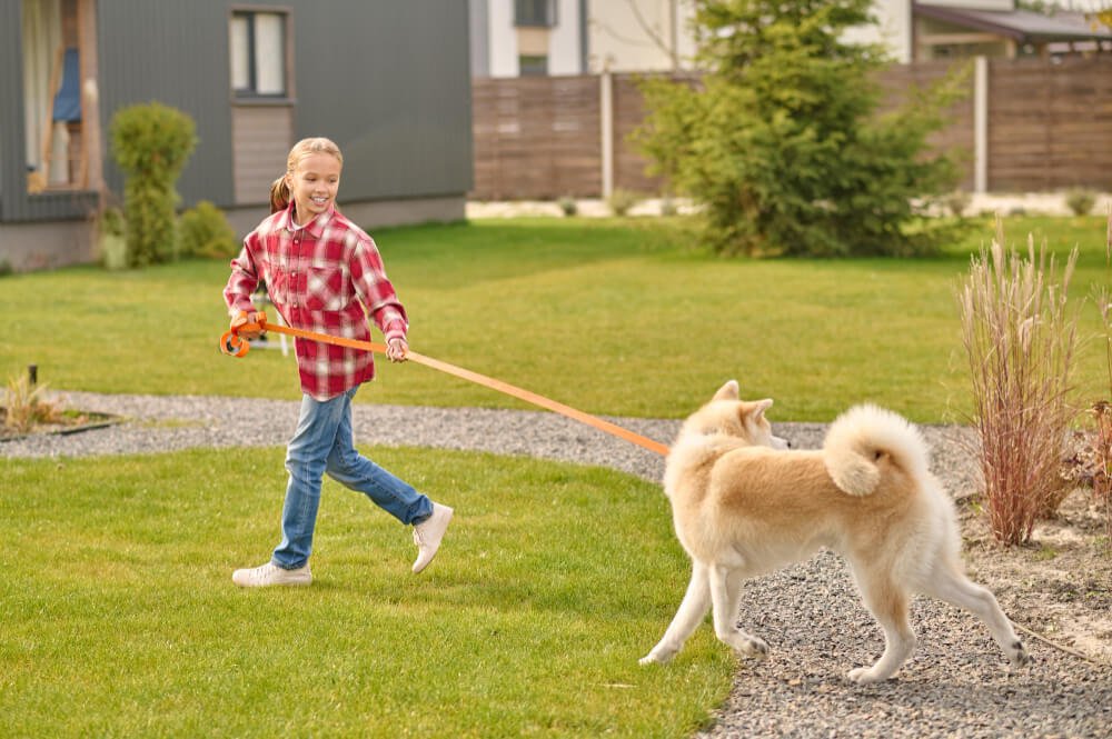Girl holding leash running looking at dog
